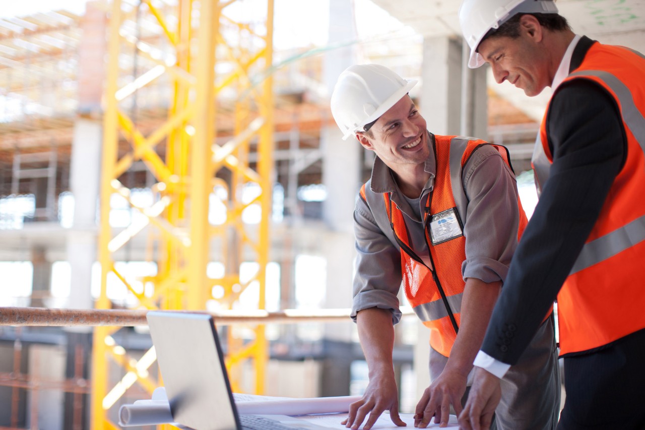 Construction workers reading plans and smiling