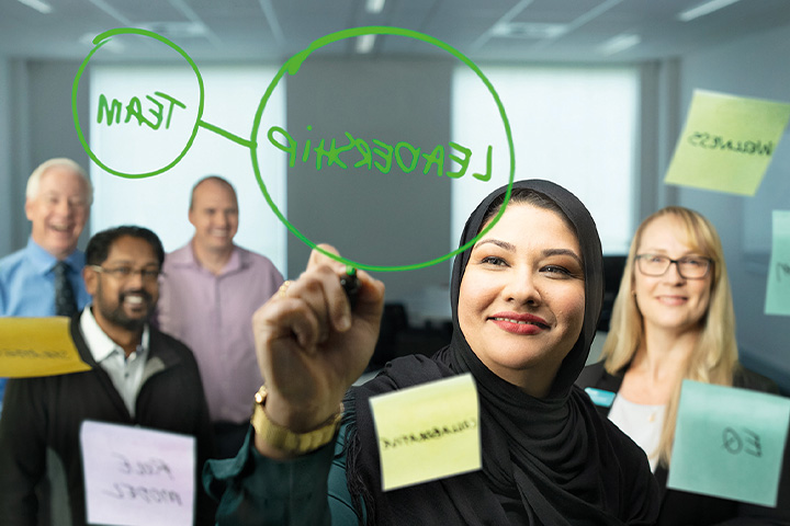A woman wearing a hijab leads a brainstorming session with her colleagues.