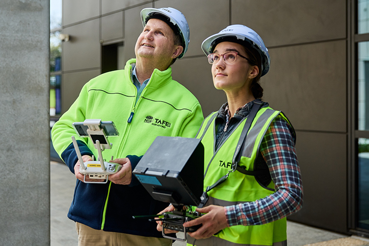 Civil engineering student operating a drone with her teacher observing