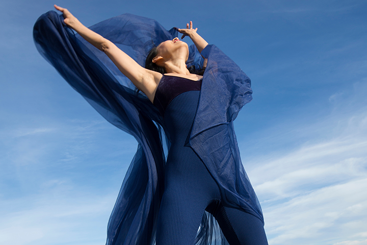 Woman posing while looking up at the clear blue sky