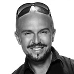 Black and white headshot of Alex Perry, smiling.