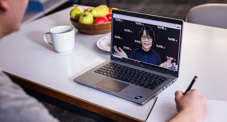 A student sits at their laptop, engaged in a video conference with a TAFE NSW teacher.
