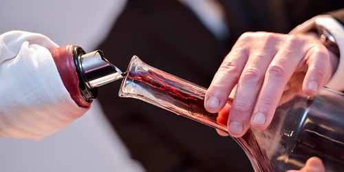 Close up sommelier image showing red wine being poured into a decanter.