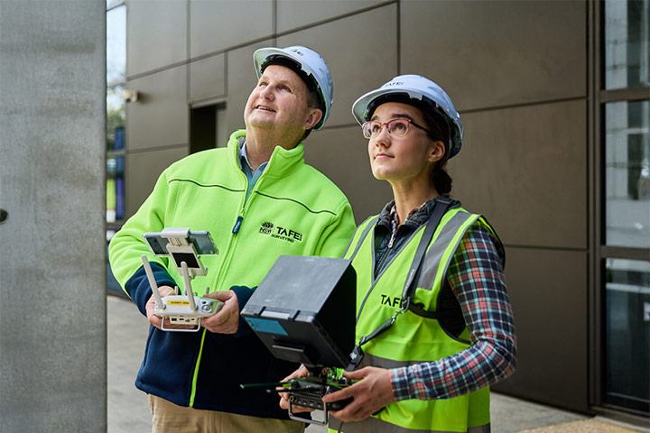 Civil engineering student operating a drone with her teacher observing