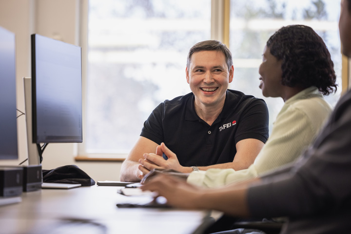 A male TAFE NSW staff member and a female student are seated at a desk, focused on a computer screen and engaged in a collaborative task.