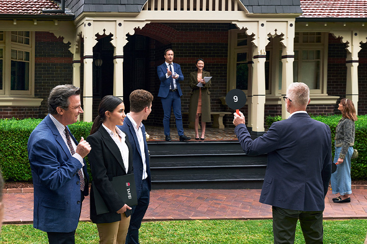 Teacher and students actively participating in a residential auction, gaining practical insights into the dynamics of the property market.