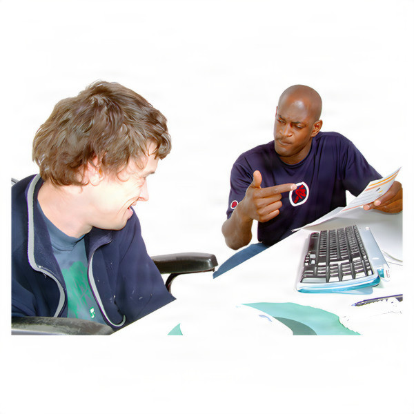 Two men having a discussion at a desk with a computer keyboard and mouse.