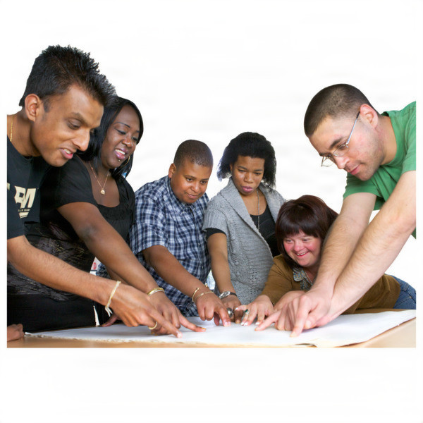 A diverse group of six people pointing at something on a table.