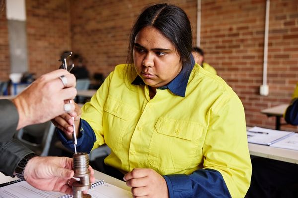 Person learning to use a tool with support from another person.