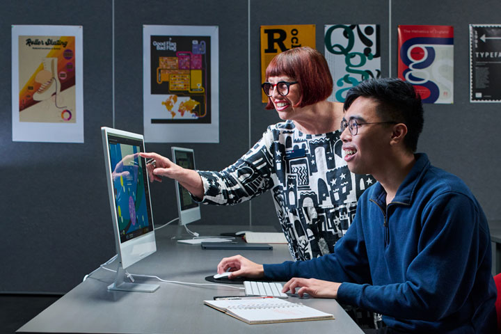 A young male student collaborates with his teacher on a design project, receiving guidance and feedback.