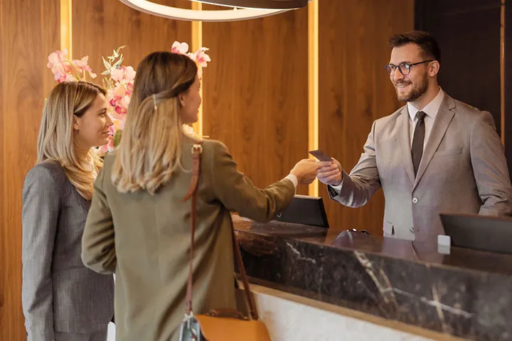 Hotel receptionist checking in two customers.