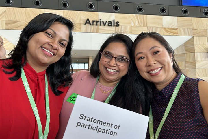 Navi Sapin and 2 of her fellow graduates from the TAFE NSW Certificate I in Aviation class stand below the ‘Arrivals’ hall sigh at the new Western Sydney International Airport, proudly holding a Statement of Participation.