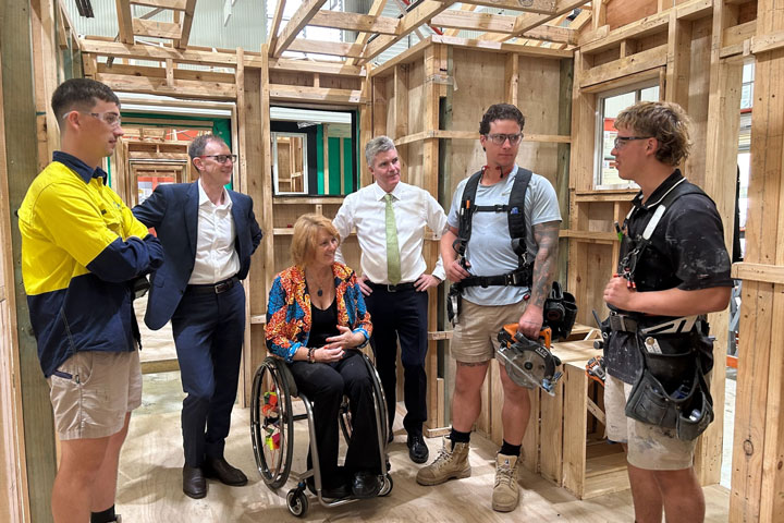 Member for The Entrance, Member for Gosford and Minister for Skills, TAFE and Tertiary Education standing together wearing corporate professional clothing. They are talking to TAFE NSW students and teachers in shorts, work boots and safety glasses.