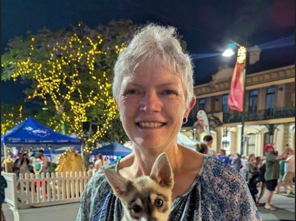 Cancer survivor Karrie Biggart holding a dog, embracing her new career as a vet nurse.