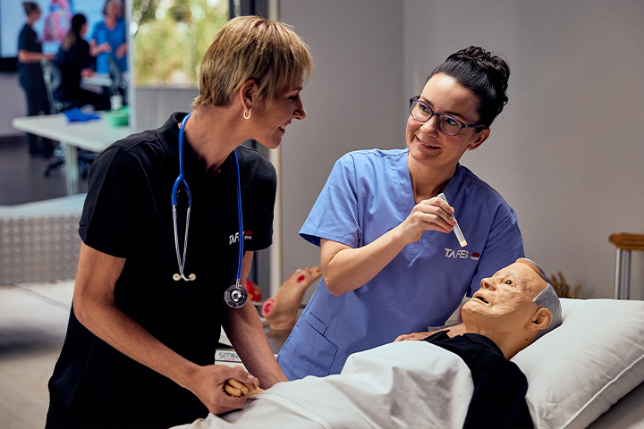 Nursing teacher and student practicing skills on a mannequin in a TAFE NSW Mobile Training Unit.