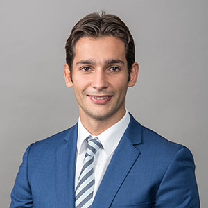 Cassiano, a professional in a blue suit and striped tie.