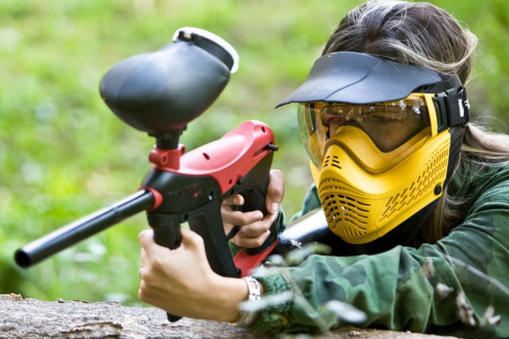 Person holding a paintball gun while wearing protection.