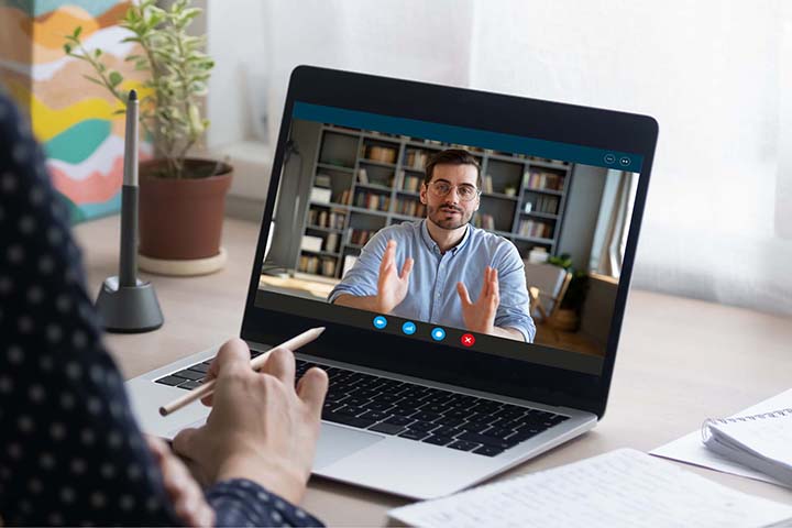 A woman working on her laptop in her home office, participating in a Zoom call.